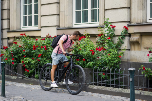 Junger Mann auf dem Fahrrad betrachtet Blumen
