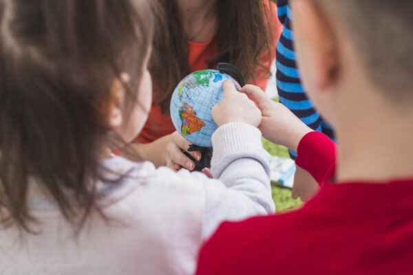 Kinder zeigen auf einen Globus